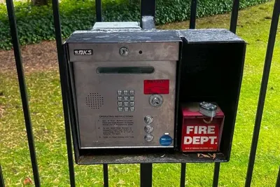 An intercom station mounted beside a pedestrian gate