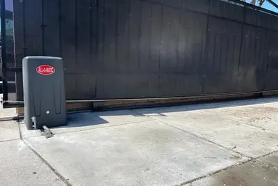An All-O-Matic slide gate operator housing beside a driveway gate track