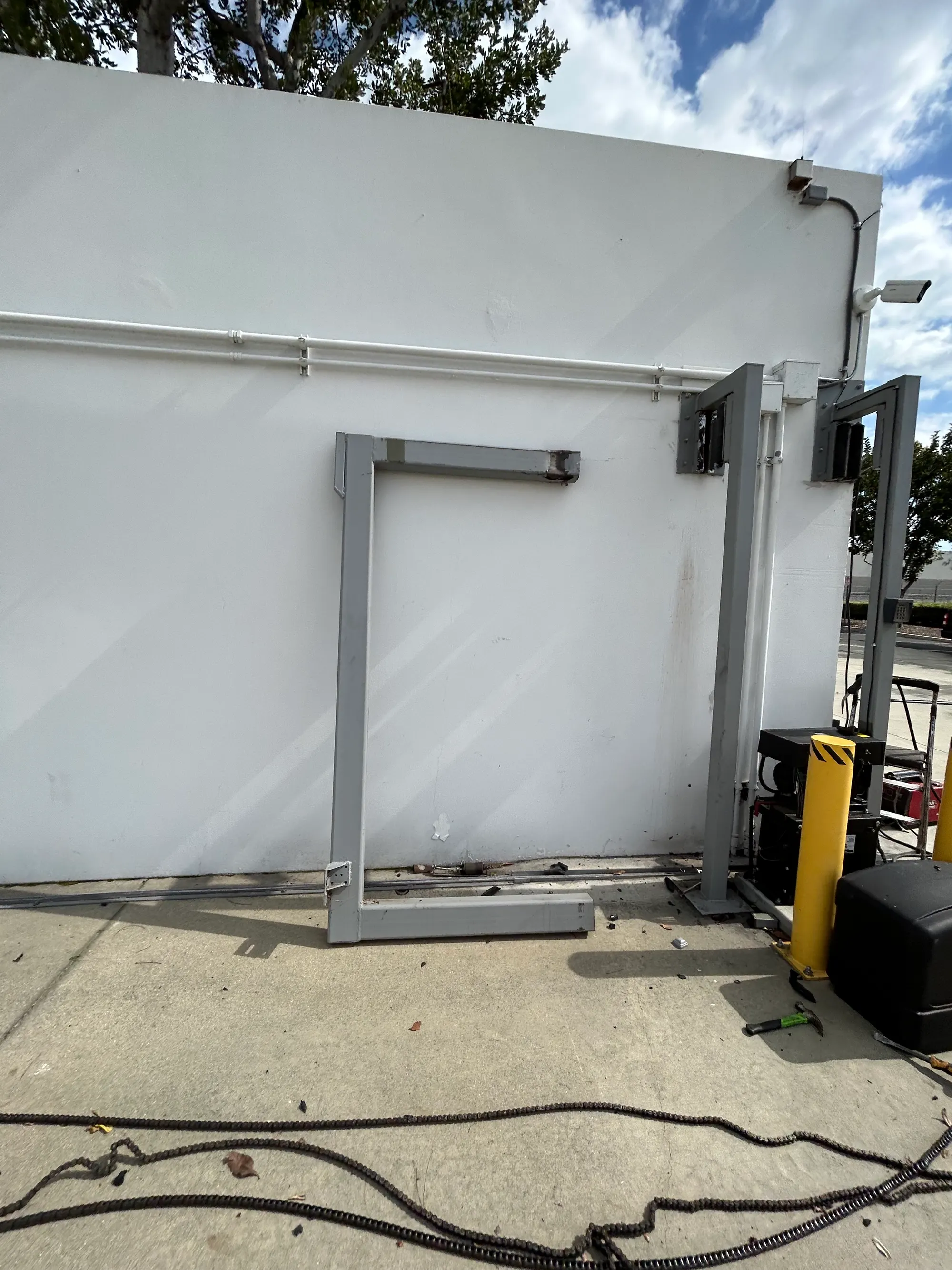 The gate frame propped against a warehouse wall with a forklift alongside during the repair