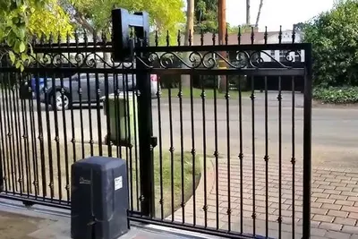 An electric driveway gate with its operator and power supply mounted alongside