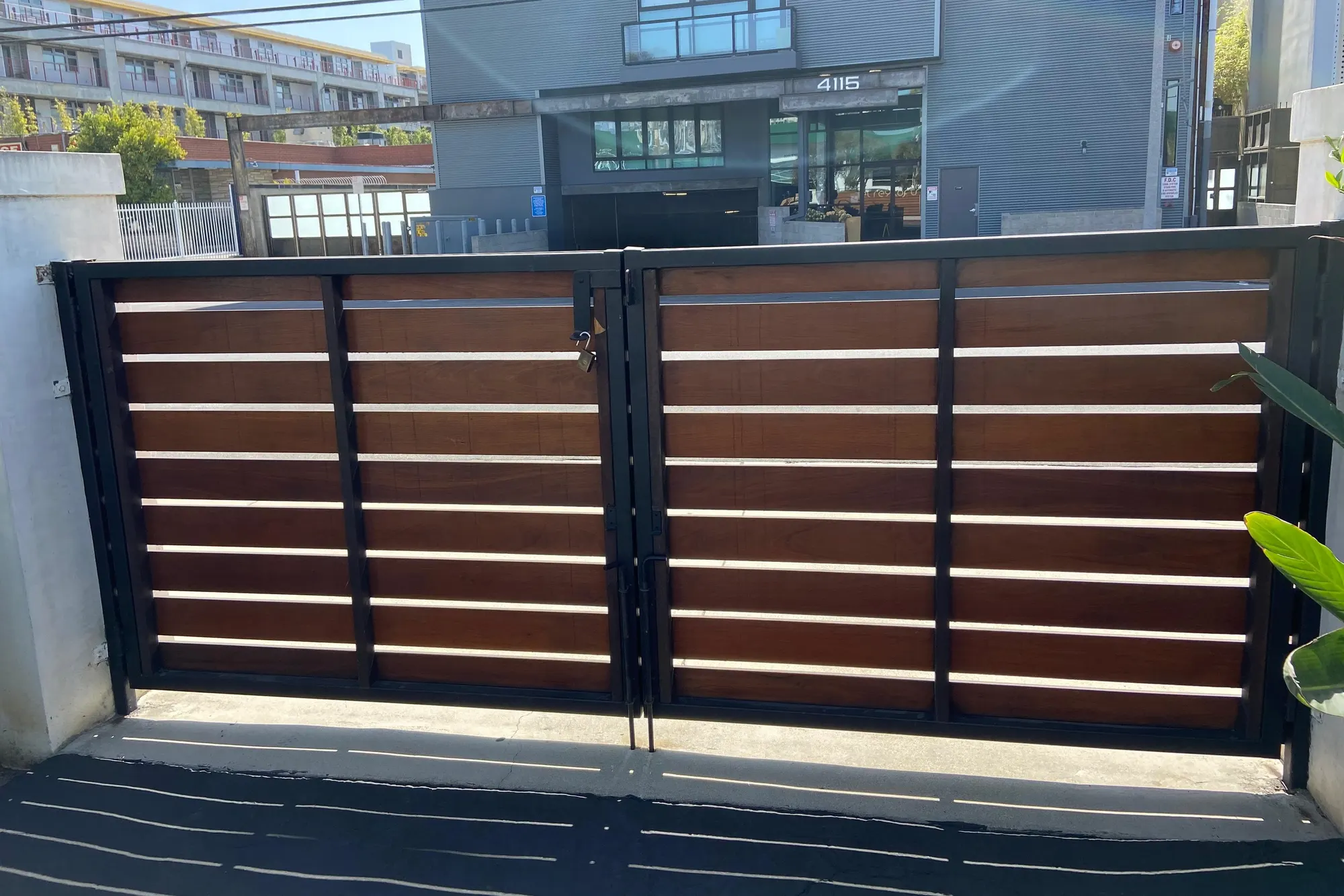 A horizontal-slat wood and steel driveway gate closed across a paved entrance