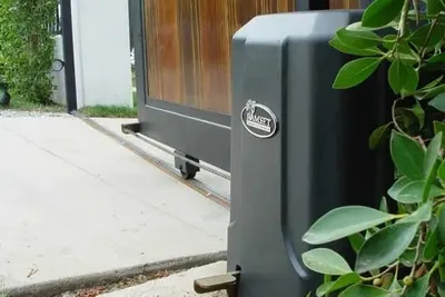 A gate operator mounted on a concrete pad at the end of a sliding driveway gate