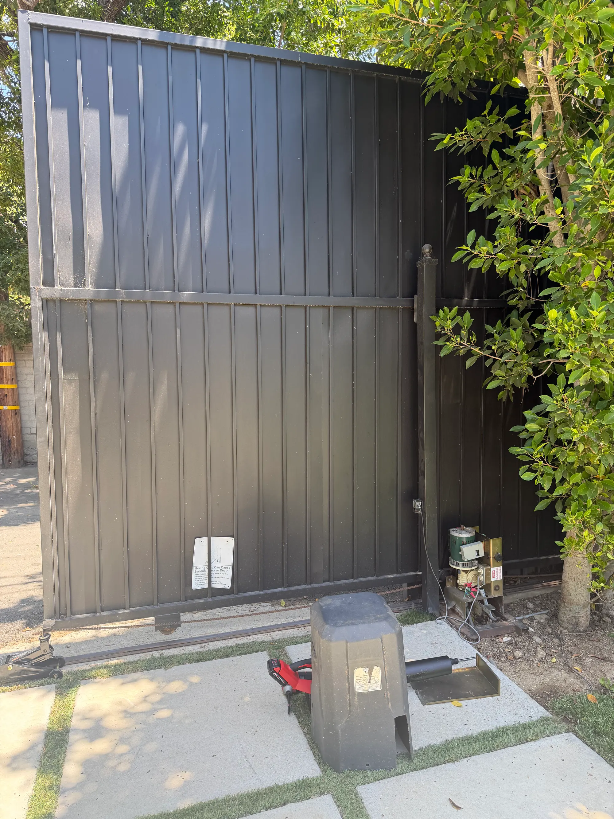 The gate held clear of its track during the repair, with the operator and toolbox on the driveway behind