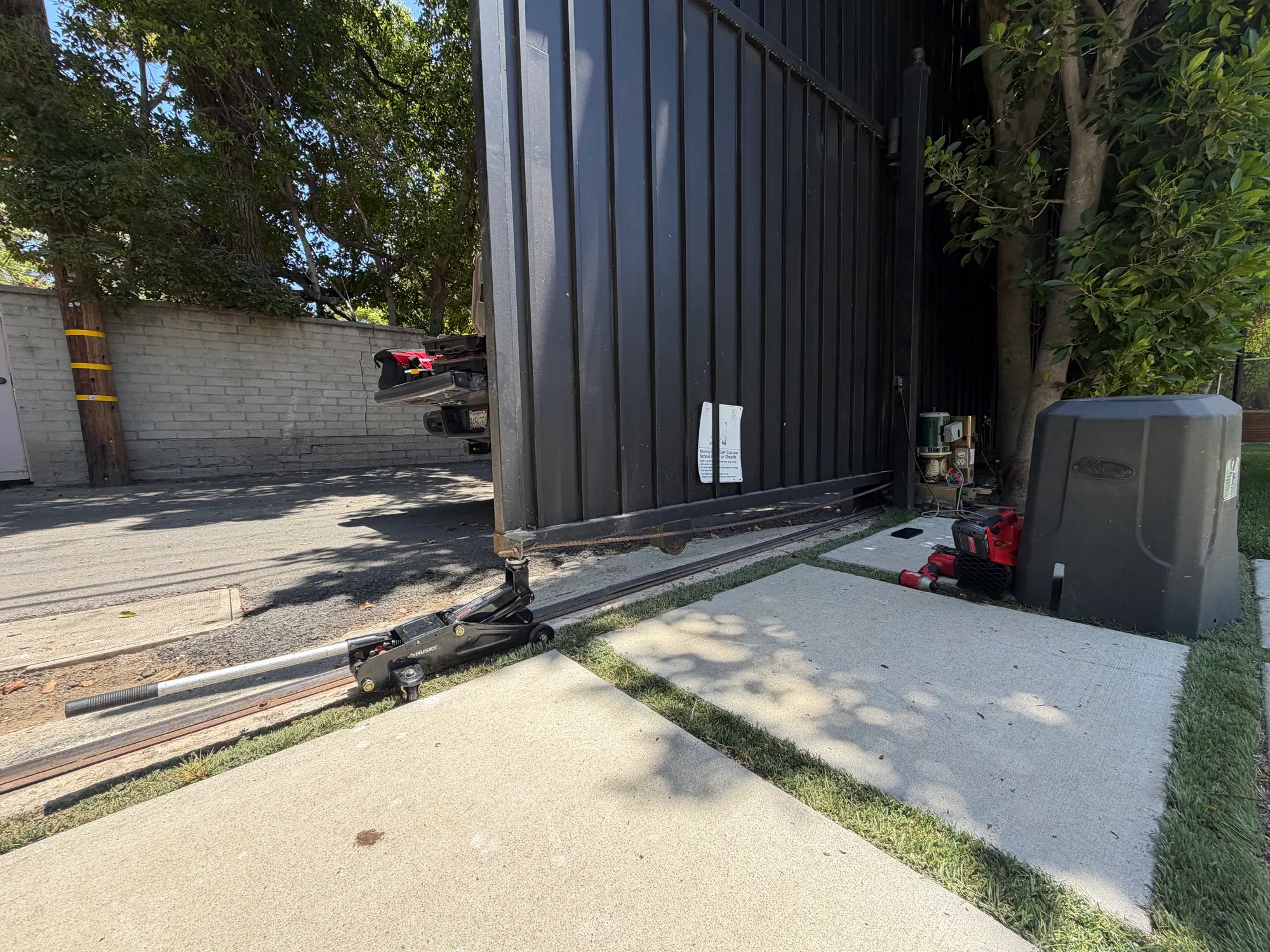 A floor jack positioned under the leading edge of the slide gate to take its weight while the rollers are replaced